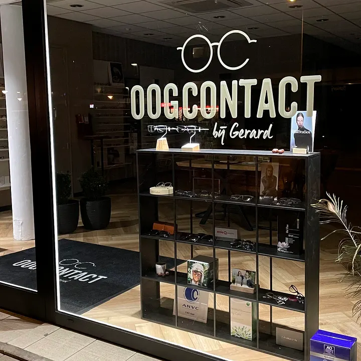 De verlichte etalage van de winkel in de avond, met het logo op het glas.